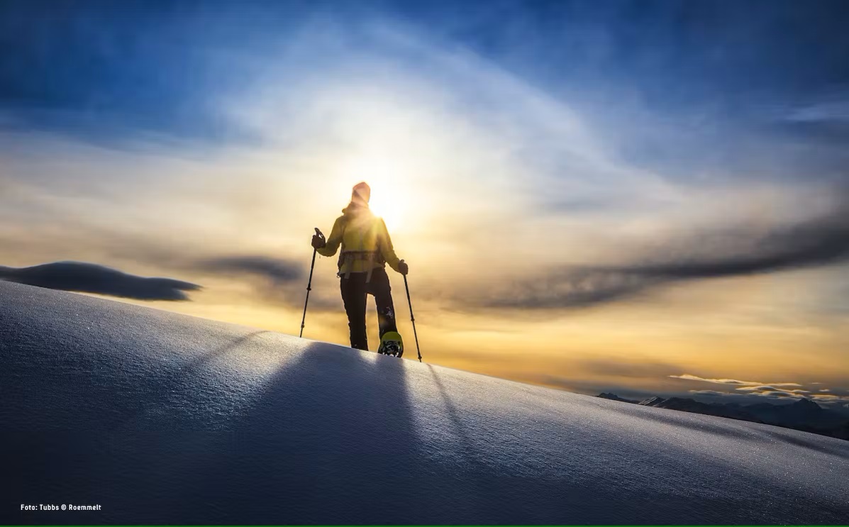 Bild Wintersportler mit Schneeschuhen am Berg bei Sonnenuntergang
